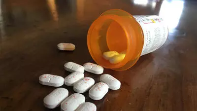 Prescription medication bottle with pills spilled on a table