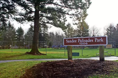 Sign at Sandee Palisades Park in Troutdale with trees and a grassy area in the background