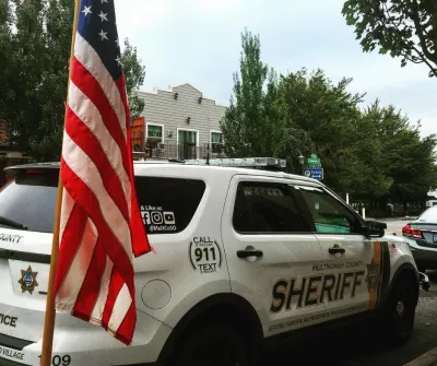 Multnomah County Sheriff vehicle parked next to an American flag in downtown Troutdale