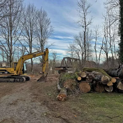 Backhoe and logs at the construction site of the Sandy River Park and Trail