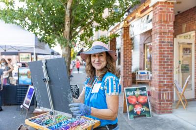 An artist smiles while paining during First Friday