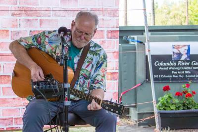 A man plays guitar at First Friday in downtown Troutdale