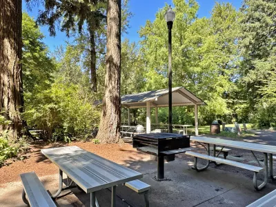Picnic tables and a grill next to a picnic shelter at Glenn Otto Park