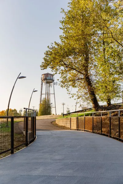 Troutdale's historic water tower rises above a paved trail next to a tree that is just starting to change into fall colors