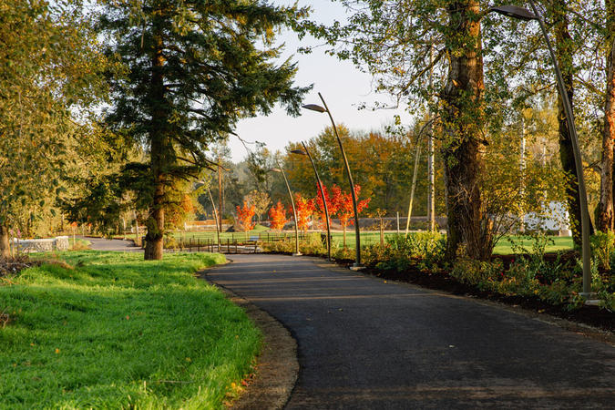 Paved walkway passes under trees at Sharon Nesbit Heritage Park