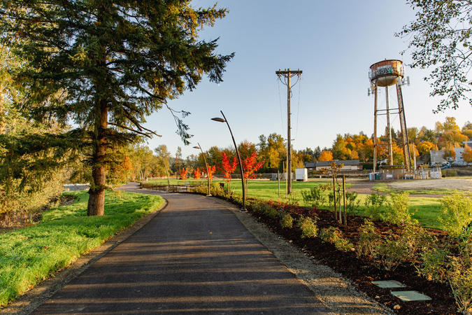 Paved walkway curves past the historic water tower at Sharon Nesbit Heritage Park