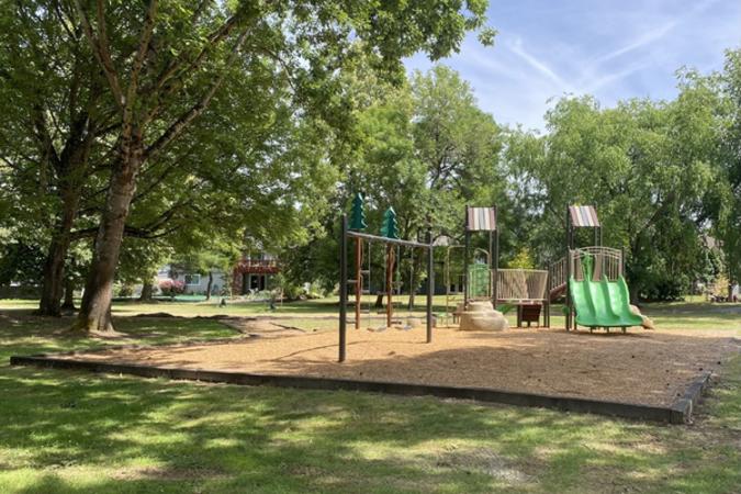 Trees tower over a play structure at Sandee Palisades Park